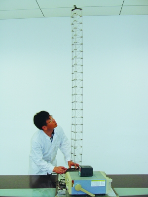 這是伸展開(kāi)的衛(wèi)星太陽(yáng)能電池用盤(pán)壓伸桿，20厘米長(zhǎng)螺旋狀的盤(pán)壓伸桿（右側(cè)小圖）打開(kāi)后能達(dá)2米長(zhǎng)（8月7日攝）。（新華社發(fā)）